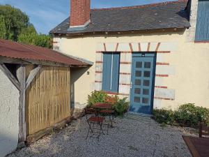 une maison avec une porte bleue, une table et des chaises dans l'établissement Le Roi des chats, gîte proche de Beauval et des châteaux, à Mareuil-sur-Cher