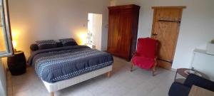 a bedroom with a bed and a red chair at Au Petit Galop in Nassiet +12 photos