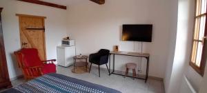 a bedroom with a bed and a desk with a television at Au Petit Galop in Nassiet