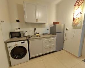 a kitchen with a washing machine and a refrigerator at apartments with separate kitchen by the sea in Ashdod +6 photos
