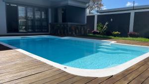 a swimming pool with a wooden deck and a house at Calodyne Mauritius in Calodyne +5 photos