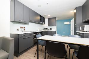 una cucina con armadi grigi, tavolo e sedie di Beckett House near Dublin City Centre a Dublino