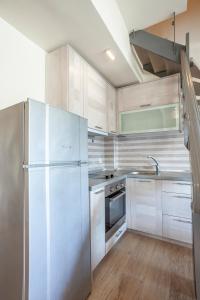 a kitchen with white cabinets and a stainless steel refrigerator at Apartments Enastron 44 2 bedroom in Pefkochori