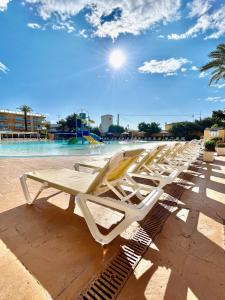 rzędu białych leżaków przy basenie w obiekcie Apartamentos Turisticos Terralta w mieście Benidorm