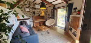 a living room with a blue couch and a piano at Adorable maison cévenole in Bez-et-Esparon