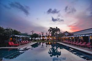 a resort pool with chairs and a sunset in the background at Golden Bay Cottage - SHA Extra Plus in Ko Lanta