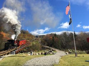 a train is coming down the tracks with smoke at 65PT New Log Cabin in Private Setting. Hot tub. Gym/Pool Access! in Twin Mountain
