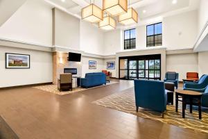 a lobby with a waiting room with blue chairs at Comfort Suites Rensselaer near Fair Oaks in Rensselaer