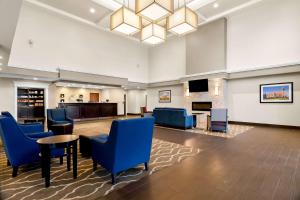 a hotel lobby with blue chairs and a fireplace at Comfort Suites Rensselaer near Fair Oaks in Rensselaer