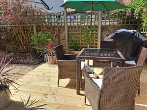 a patio with a table and chairs and an umbrella at Dumble Cottage in Minehead