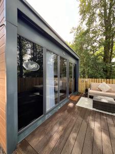 un patio grillagé avec un canapé sur une terrasse en bois dans l'établissement Ravenswood Pod, à Fort William