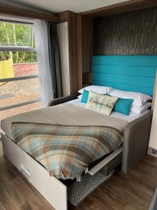 a bedroom with a large bed with a blue headboard at Ravenswood Pod in Fort William