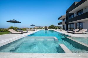 a swimming pool with lounge chairs and a building at Omnia Luxury Villa, 100m2 Pool, Whirlpool & Gym, By ThinkVilla in Prínos +56 photos