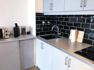a kitchen with a sink and a black tile wall at Rheinblick Apartments in Cologne