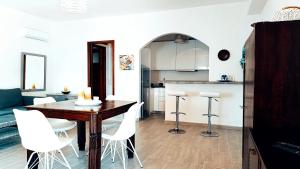eine Küche und ein Esszimmer mit einem Holztisch und weißen Stühlen in der Unterkunft ZEN PLACE in Kouniádhoi
