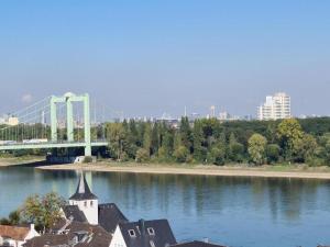 a bridge over a river with a church and a building at Rheinblick Apartments in Cologne +29 photos