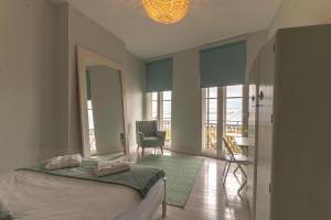 a bedroom with a bed and a chair and windows at Seaview Apt Turner Contemporary, Margate By Adliv in Margate