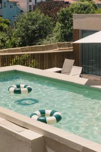 una piscina con dos sillas de jardín y dos flotadores en Outsite Porto Mouco, en Oporto