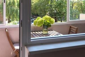 a vase of flowers sitting on a table in a window at Algirdo Apartments, Self Check-in, Free Private Parking in Vilnius +24 photos