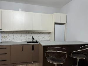 a kitchen with white cabinets and a counter with two chairs at House in the Bamboos in Batumi +5 photos