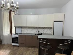 a kitchen with white cabinets and a counter with stools at House in the Bamboos in Batumi