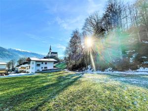 a sun shines on a field with a church in the background at Apartment Ferienwohnung Selina by Interhome in Fügenberg