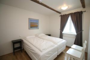 a bedroom with a white bed and a window at Acco Ice Apartments in Akureyri