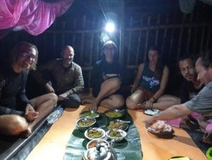 a group of people sitting around a table with plates of food at Backpacker Lodge in Bukit Lawang