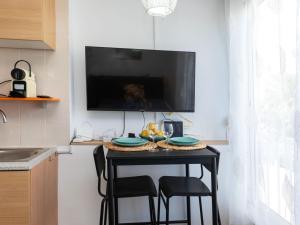 cocina con mesa con sillas y TV en la pared en Studio Beach La Pineda by Interhome, en La Pineda