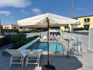 eine Terrasse mit Sonnenschirm und Stühlen sowie ein Pool in der Unterkunft Hotels Campus in Collecchio