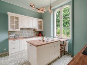 una cocina con armarios blancos y paredes verdes en Villa Blanc Castel by Interhome, en Saint-Briac-sur-Mer