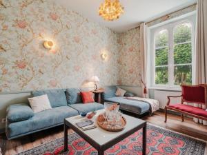 Una sala de estar con un sofá azul y papel tapiz floral. en Villa Blanc Castel by Interhome, en Saint-Briac-sur-Mer