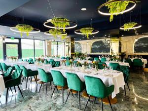 a room with tables and green chairs and chandeliers at Ambar Hotel in Giurgiu