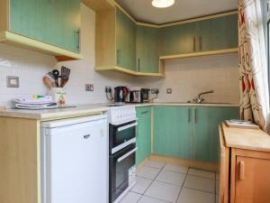 a kitchen with green cabinets and a white dishwasher at Constantine Bay in Padstow +7 photos