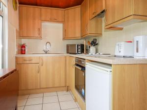 a kitchen with wooden cabinets and a white appliance at Newtrain Bay in Padstow
