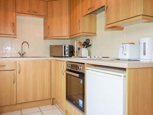 a kitchen with wooden cabinets and a dishwasher at Newtrain Bay in Padstow +5 photos