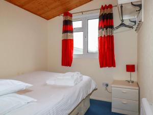 a bedroom with two beds and red curtains at Newtrain Bay in Padstow