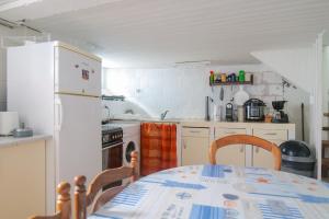 a kitchen with a table and a white refrigerator at Maison mitoyenne cœur de ville à deux pas du port de pêche et de la plage Les Sables - 6 personnes in Les Sables-dʼOlonne