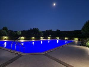 a blue swimming pool at night with lights at Sunset studio in Shartrez in Shkorpilovtsi +7 photos