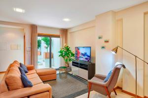Una sala de estar con un sofá y un televisor. en Beautiful Town Centre Townhouse With Shared Pool, en Tavira