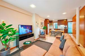 Una sala de estar con un sofá y un televisor. en Beautiful Town Centre Townhouse With Shared Pool, en Tavira