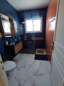 a bathroom with a marble floor with a toilet and a sink at Au Pti' Bonheur in Saint-Coulomb