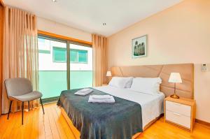 a bedroom with a bed with a chair and a window at Stunning Townhouse With Pool In Tavira Centre in Tavira +20 photos