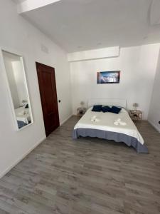 a white bedroom with a bed and a wooden floor at Maison Margot in Pozzuoli