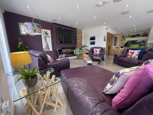 a living room with purple furniture and a glass table at 5 Bed House-Sleeps 14-Hot Tub-Bar-Garden-Parking in Tavistock