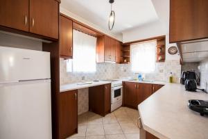 a kitchen with wooden cabinets and a white refrigerator at Sea & Mountain Horizon by Myrto in Diakopto +15 photos