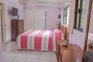 a bedroom with a bed with a red and white striped blanket at Casa grande y privada, jardín & estacionamiento in Salina Cruz +3 photos
