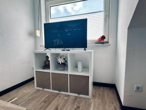 a television on a white cabinet in a room with a window at Apartment OchtrUP I Ruhig & Geräumig in Ochtrup