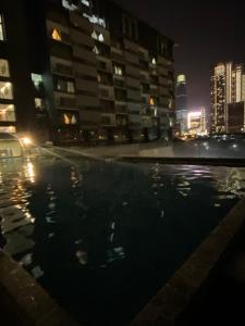 a swimming pool in a city at night at WakakaPackers in Kuala Lumpur