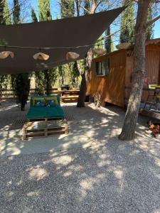 a bed under a tent in the shade of a tree at Superbe Roulotte de charme in Bagnols-en-Forêt